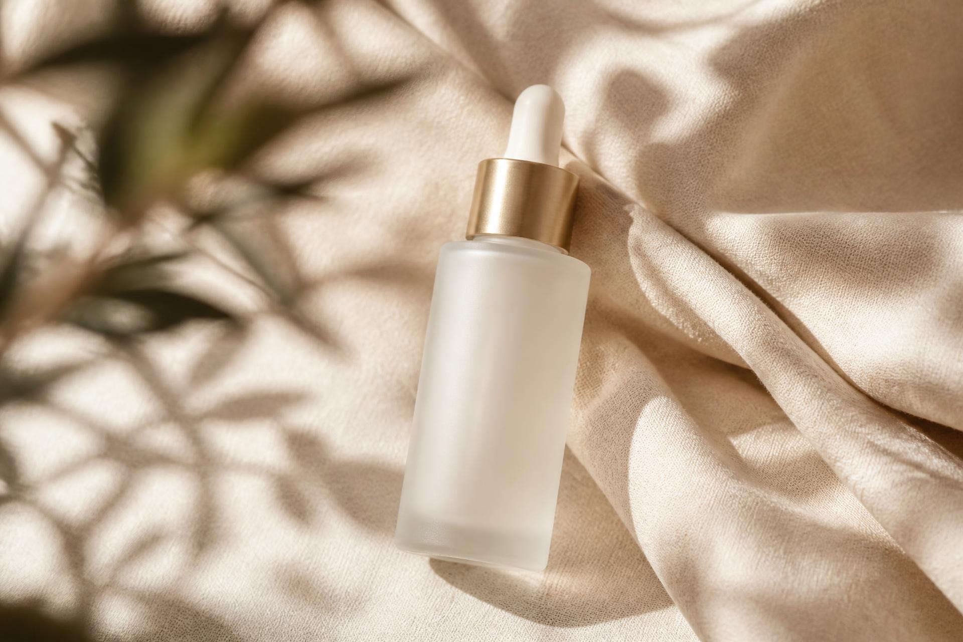 A cream skincare bottle resting on linen in warm daylight